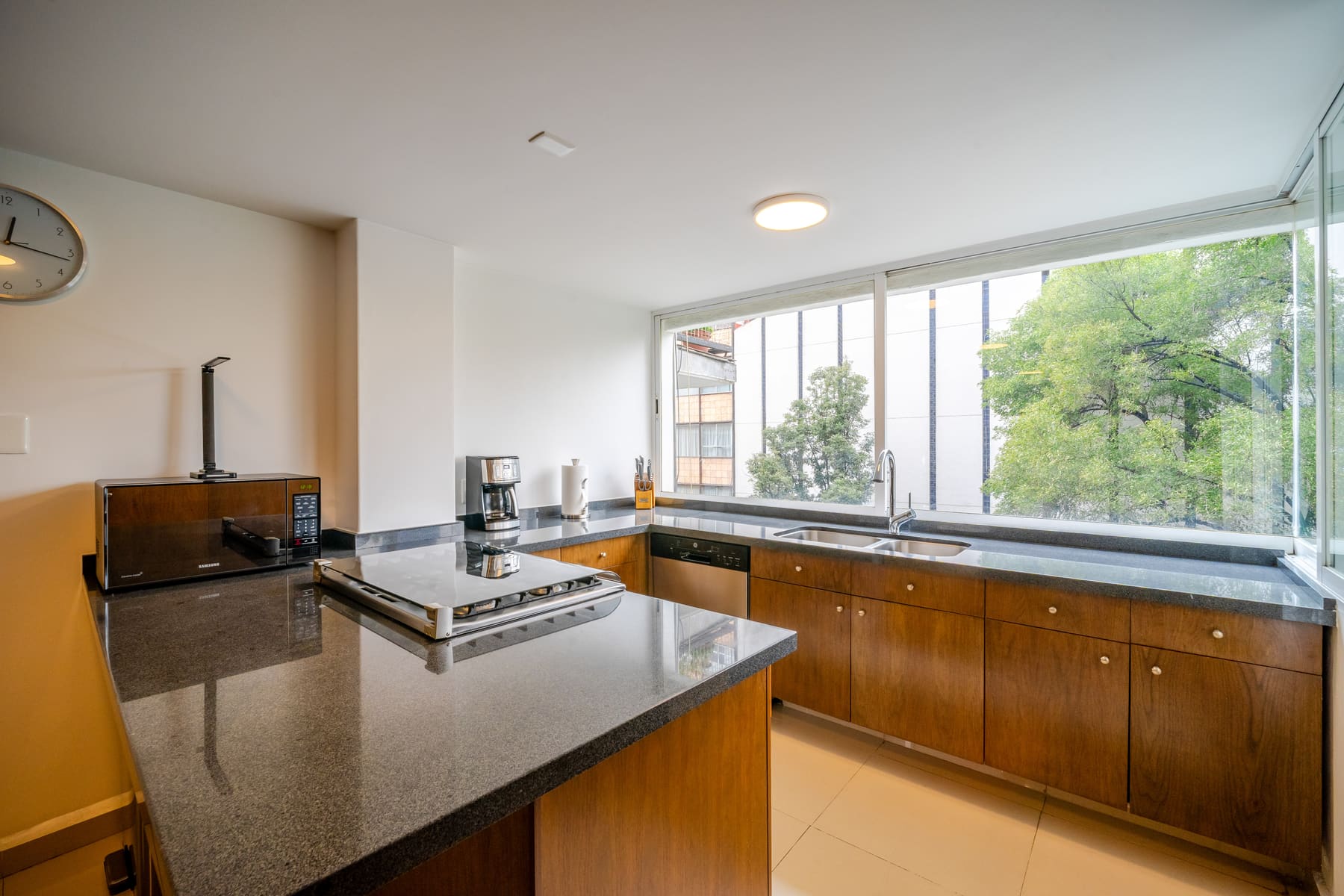 Cocina remodelada con barra de granito y ventana hacia los árboles