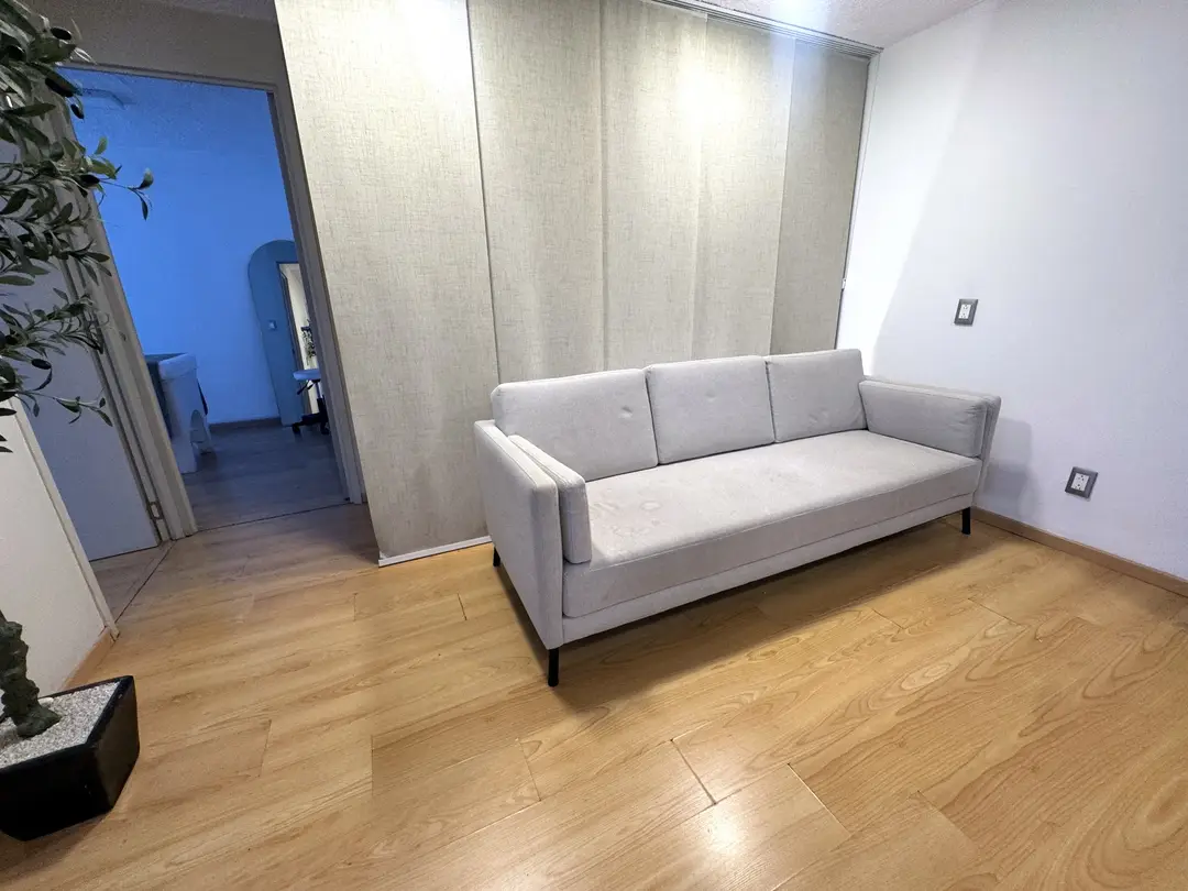 Sala con sillón claro y acceso a las cabinas
